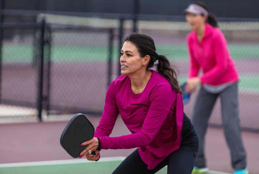 Players enjoying a competitive pickleball match at an outdoor court with scenic surroundings