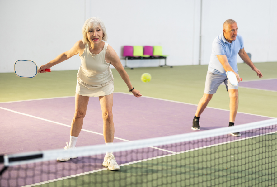 Indoor pickleball courts with players engaged in a fast-paced match under bright lighting