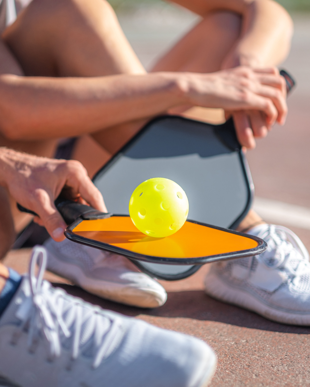 Pickleball player choosing gear for safety—paddles, shoes, & wrist supports.