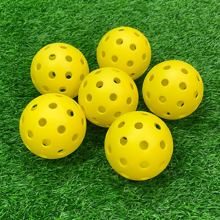 
Yellow perforated pickleball balls on grass